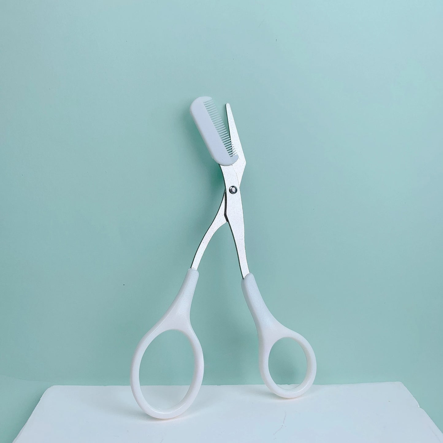 Pink eyebrow trimming scissors with built-in comb - stainless steel, precise grooming tool, creating perfect eyebrows.